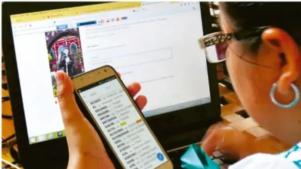 Fotografía de una persona usando un teléfono inteligente frente a una computadora portátil, ilustrando el uso cotidiano de la tecnología.