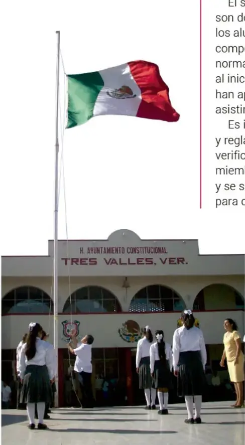 Fotografía de una ceremonia escolar en el patio de una escuela de Tres Valles, Veracruz. Se observa la bandera de México izada en un mástil, frente al edificio con el letrero 'H. AYUNTAMIENTO CONSTITUCIONAL TRES VALLES, VER.'. Varios estudiantes con uniforme escolar forman fila y una persona adulta iza la bandera.