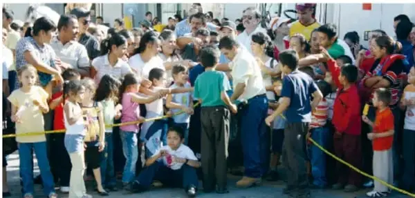 Multitud de personas observando un desfile en la calle, con niños y adultos.