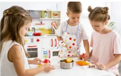 Tres niños (un niño y dos niñas) jugando con utensilios de cocina en un espacio con estantes y alimentos.