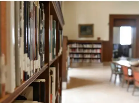 Fotografía de una biblioteca con estantes llenos de libros y mesas de lectura.
