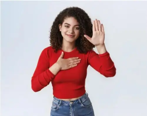 Joven con camiseta roja y jeans haciendo un gesto de alto con la mano derecha y la mano izquierda en el pecho.