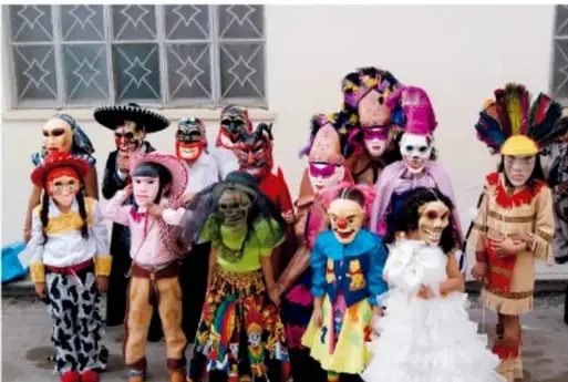 Grupo de niños y adultos disfrazados con trajes y máscaras tradicionales de la fiesta de Xantolo.
