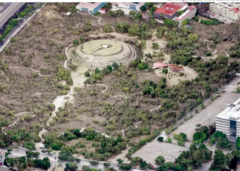 Fotografía aérea de la zona arqueológica de Cuicuilco, en la Ciudad de México, donde se observa una estructura circular rodeada de vegetación y calles.