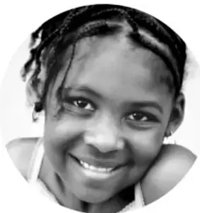 Retrato en blanco y negro de una niña sonriente con trenzas, mirando a la cámara.
