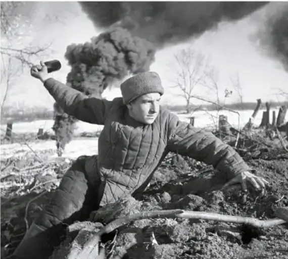 Fotografía histórica en blanco y negro de un soldado soviético con gorro de piel arrojando un cóctel Molotov, con incendios y destrucción al fondo, en el contexto de la Batalla de Stalingrado.
