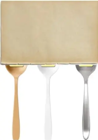 Tres cucharas (dorada, blanca y plateada) con un trozo cuadrado de margarina en la concavidad.