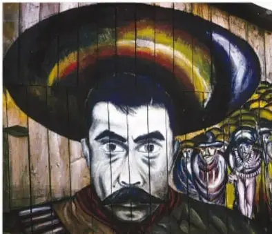 Mural con un rostro indígena con sombrero, en tonos oscuros y colores vivos, que representa la identidad zapatista.