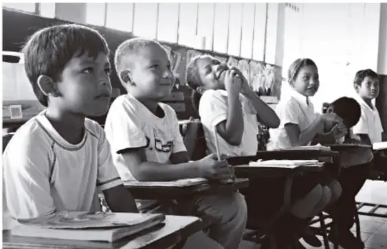 Fotografía en blanco y negro de estudiantes en un aula, atentos durante la clase.