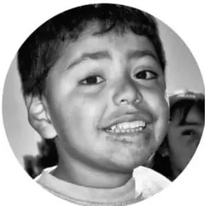 Fotografía en blanco y negro de un niño sonriente, ilustrando a los estudiantes que forman las comunidades de trabajo.