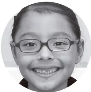 Retrato en blanco y negro de una niña sonriente con lentes.