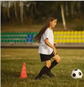 Niña jugando fútbol, ilustrando el uso de energía mecánica al patear la pelota.