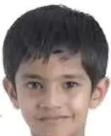 Niño acostado en el pasto soplando un diente de león. Etiqueta: spring.