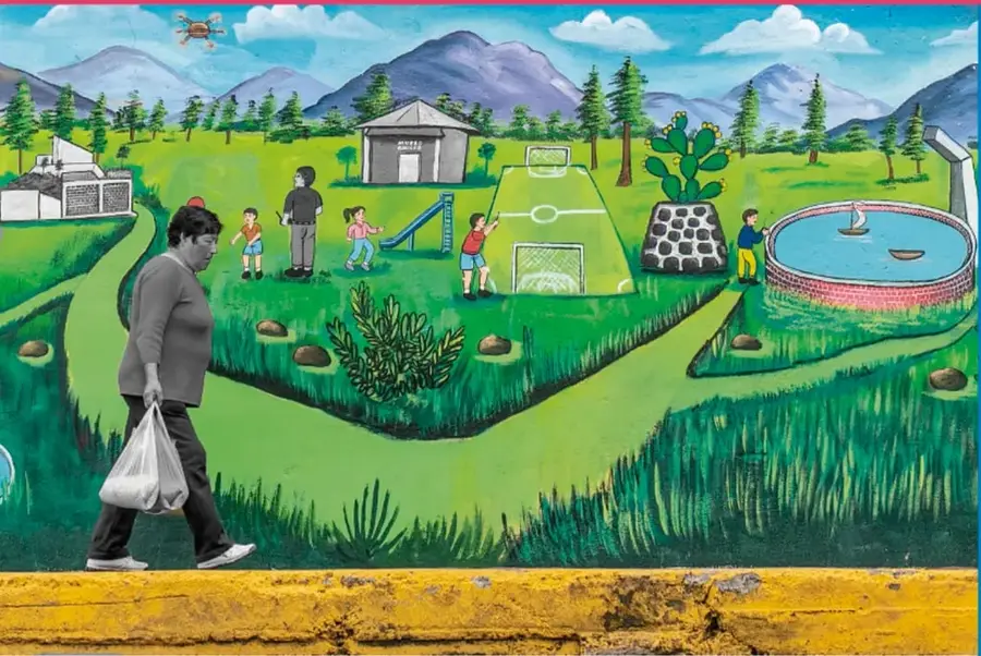 Mural pintado que muestra un paisaje rural con montañas, un campo de fútbol, juegos infantiles, una alberca, niños jugando y una persona caminando con una bolsa; obra de Marco A. López-Rosas, Estado de México.