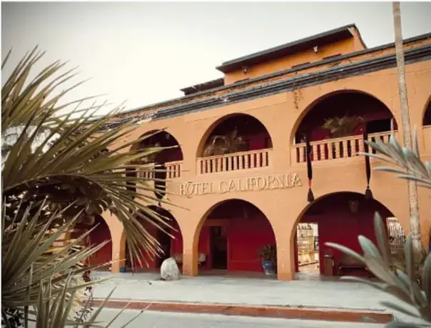 Hotel California: edificio color terracota con arcos y balcones, palmeras al frente y el nombre sobre el portal.