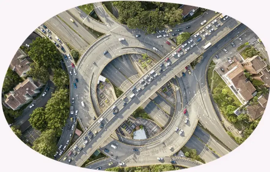 Vista aérea de un intercambio vial (enlace viales) con múltiples carriles y automóviles, ilustrando el movimiento con distintas direcciones.