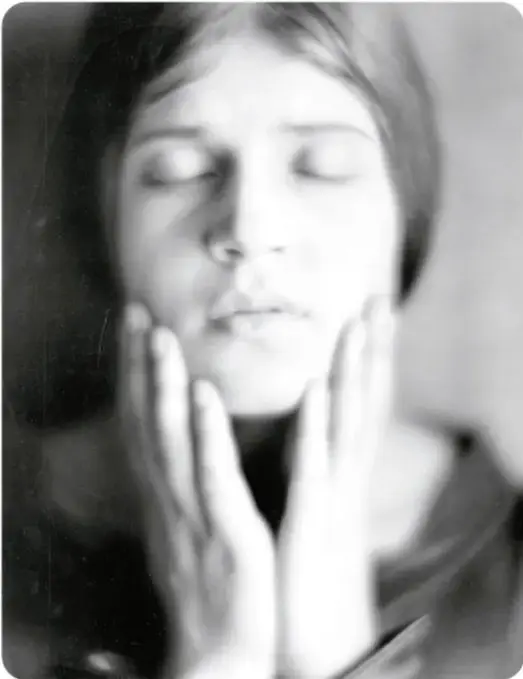 Fotografía en blanco y negro de Tina Modotti: joven de cabello recogido, ojos cerrados y manos alzadas junto al rostro, en pose serena. Pie de foto: "Modotti, retratada por Edward Weston, de quien fue asistente y aprendiz".