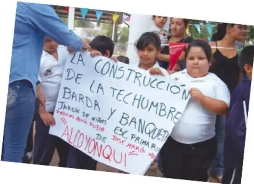 Fotografía de estudiantes y una persona adulta sosteniendo una pancarta que dice: 'LA CONSTRUCCIÓN DE LA TECHUMBRE Y BANQUETA ES PRIMARIA. JARDÍN DE NIÑOS JOSÉ MARÍA... ALLOYONQUI'.