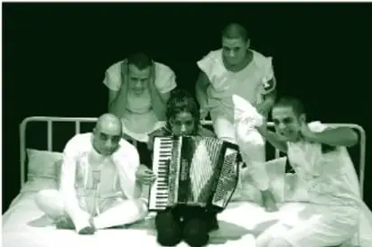 Fotografía (en tinta verde del libro) de cuatro hombres vestidos de blanco con la cara pintada y una mujer al centro tocando acordeón, todos sentados sobre una cama; uno sujeta una almohada y se tapa un oído y otro se cubre los oídos con ambas manos.
