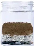 Frasco con tierra sobre el periódico y un atomizador rociando agua.