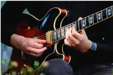 Manos tocando una guitarra eléctrica, ilustrando el concepto de música.