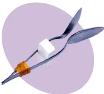 Par de cucharas metálicas unidas con una liga y una goma de borrar entre ellas.