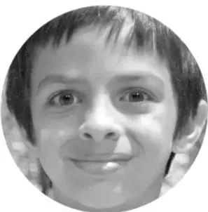 Fotografía circular en escala de grises de un niño sonriente, probablemente un estudiante participante.
