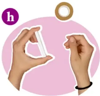 Manos colocando cinta adhesiva alrededor del tubo terminado; se ve un rollo de cinta dorada.