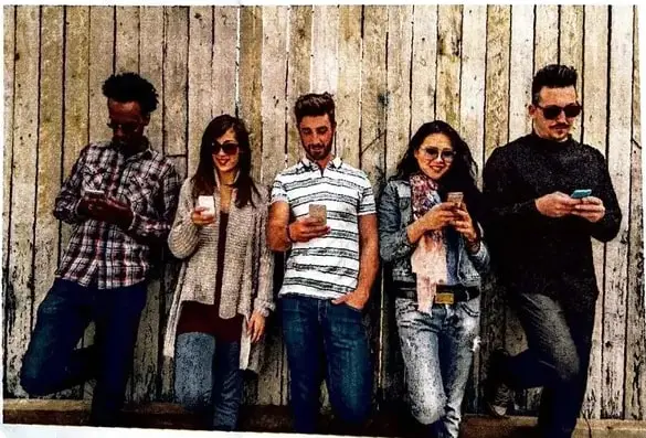 Cinco jóvenes utilizan sus teléfonos celulares apoyados junto a una pared. El pie de foto indica: «Tecnología absorbente y aislante».