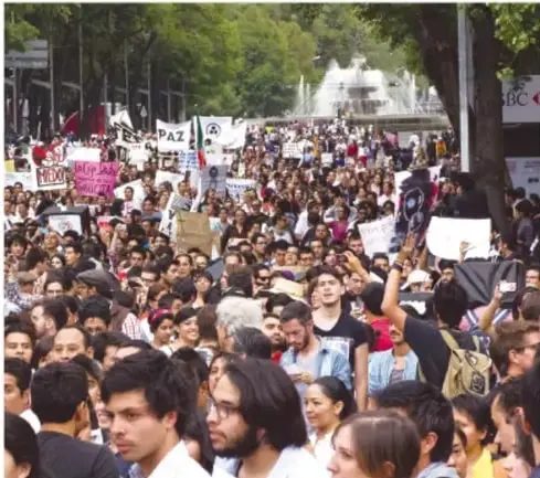 Multitud de personas marchando en una calle con pancartas, representando la participación ciudadana y la protesta social.