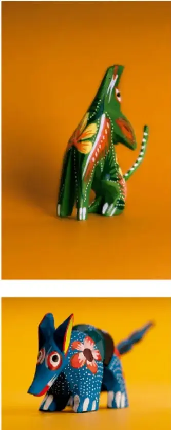 Figura artesanal mexicana (alebrije) verde con pintura de colores, en forma de animal fantastico sobre fondo naranja.