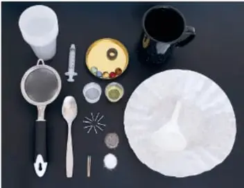 Materiales del experimento acomodados sobre fondo oscuro: vasos, cuchara, colador, filtro de papel, clavos, canicas, imán y jeringa.