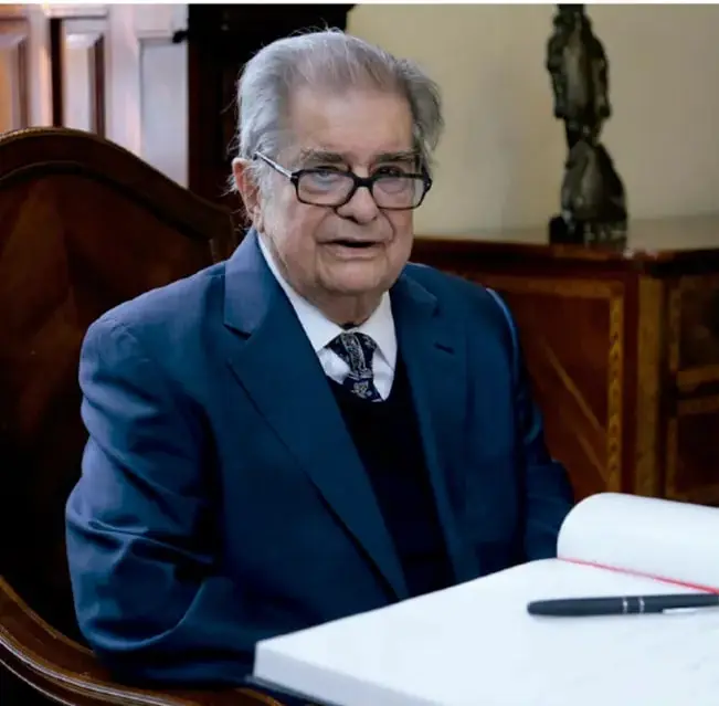 Fotografía de Miguel León Portilla, escritor e historiador mexicano, sentado ante un escritorio con libros.