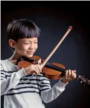 Niño tocando el violín con un arco.