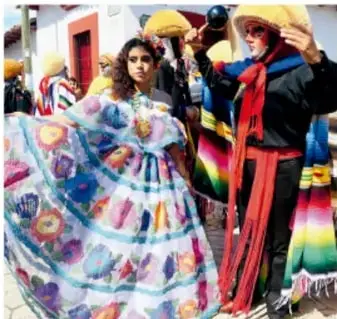 Fotografía de personas con vestimenta tradicional colorida (falda amplia, sombreros), posiblemente en una fiesta o desfile comunitario.