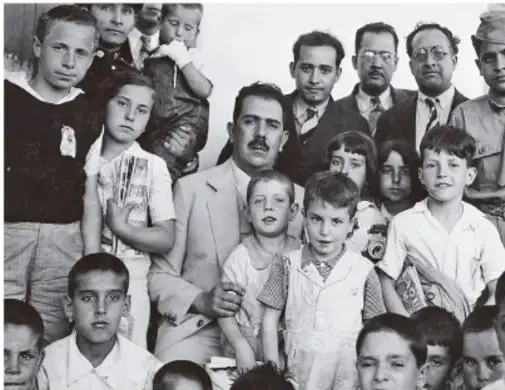 Fotografía en blanco y negro de un grupo de niños y adultos, posiblemente refugiados españoles o los niños de Morelia, acompañados por autoridades mexicanas.