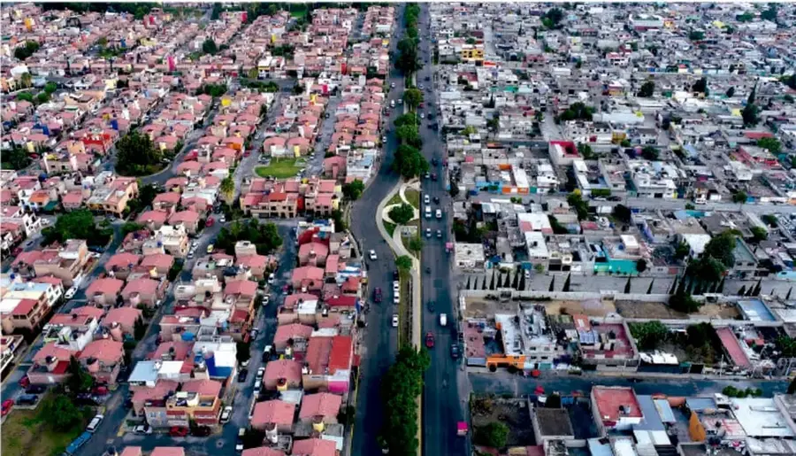 Vista aérea de una ciudad con calles, avenidas y viviendas de techos rojos, que ilustra la distribución espacial de una zona urbana.