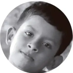 Fotografía circular en blanco y negro de un niño que sonríe, acompañando la actividad de lectura en plenaria.