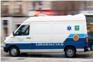 Fotografía de una ambulancia blanca con franjas azules y naranjas, con la palabra URGENCIAS y una estrella de la vida.