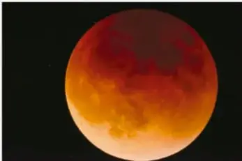 Fotografía de la Luna eclipsada, de color rojizo, en el cielo nocturno.