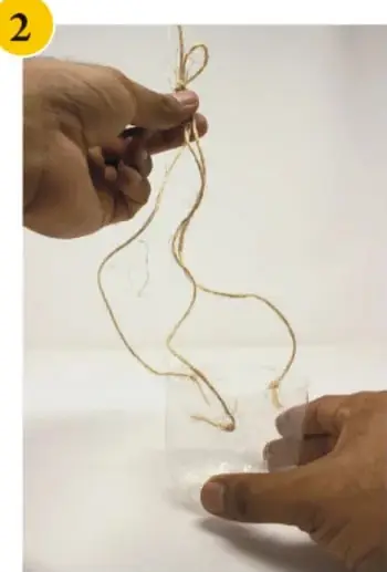 Manos pasando la cuerda por las perforaciones del recipiente y haciendo nudos.