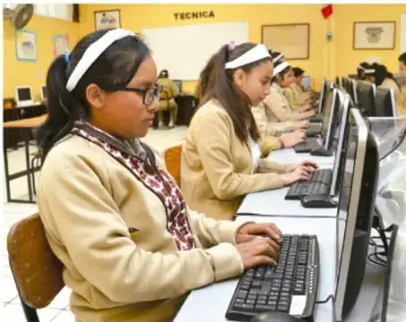 Fotografía de estudiantes en una sala de cómputo escolar usando computadoras, probablemente investigando datos estadísticos.