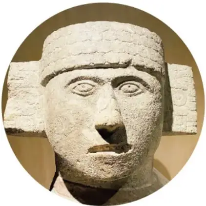 Fotografía circular del rostro de un Chac mool con tocado trenzado y expresión serena.