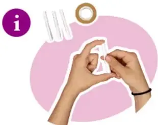 Manos presionando los extremos de un tubo de papel blanco para probar su resistencia, con tiras y cinta adhesiva al fondo.
