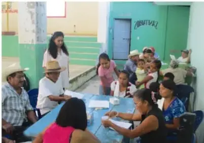Reunión comunitaria con personas sentadas alrededor de una mesa.