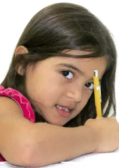 Niña con lápiz en la mano, apoyada sobre una libreta, pensando.