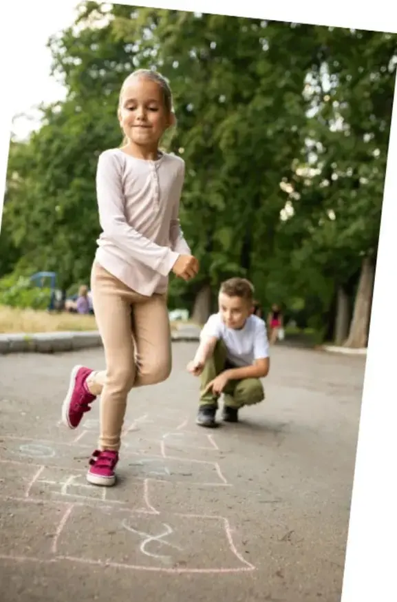 Niña corriendo y niño agachado junto a un diagrama de bebeleche en el suelo.