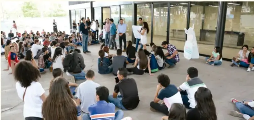 Estudiantes sentados en el patio escolar durante una actividad grupal al aire libre.