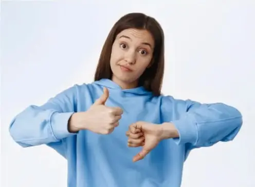 Joven con sudadera azul haciendo gestos con las manos, uno de aprobación y otro de desaprobación.