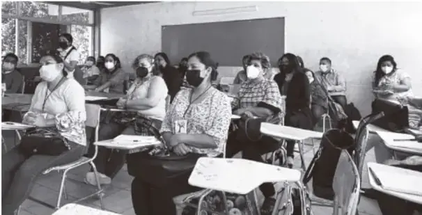 Fotografía en tonos fríos de un salón de clases con estudiantes adolescentes sentados en sillas individuales (varios con cubrebocas), aparentemente en una sesión de tutoría o trabajo colectivo.